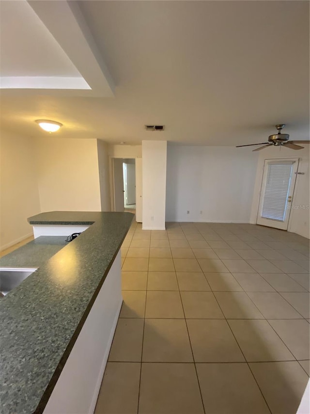 interior space featuring light tile patterned floors, a sink, visible vents, a ceiling fan, and dark countertops