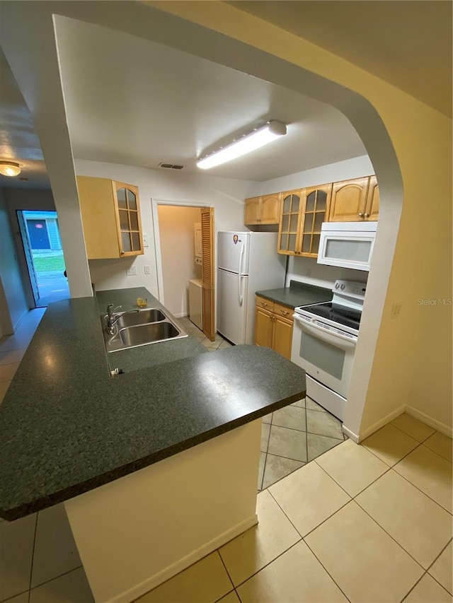 kitchen with white appliances, visible vents, dark countertops, a peninsula, and a sink