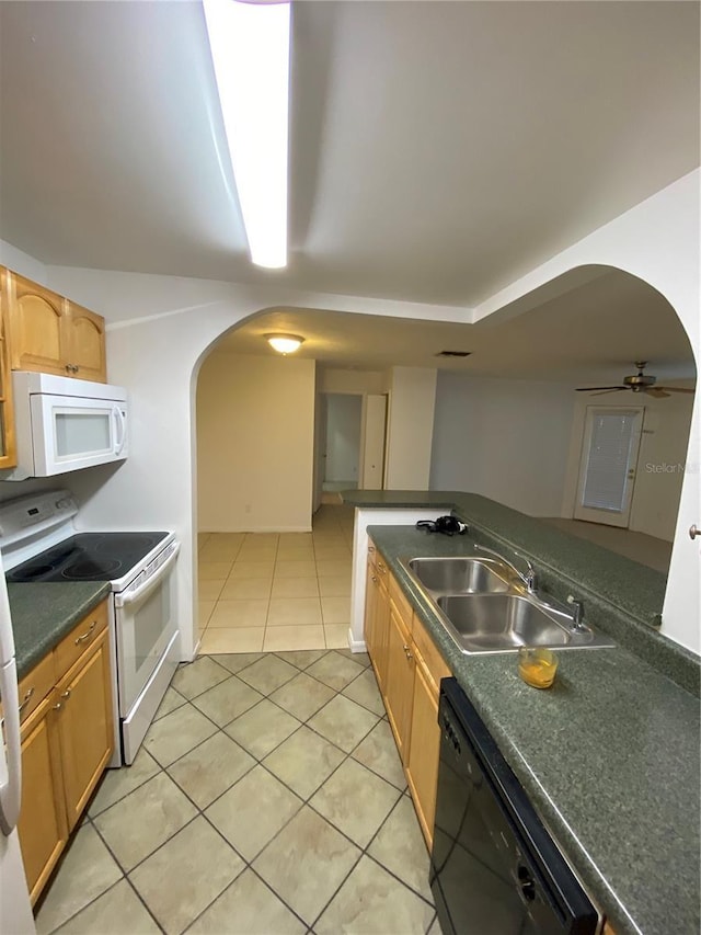 kitchen featuring arched walkways, light tile patterned floors, white appliances, a sink, and dark countertops