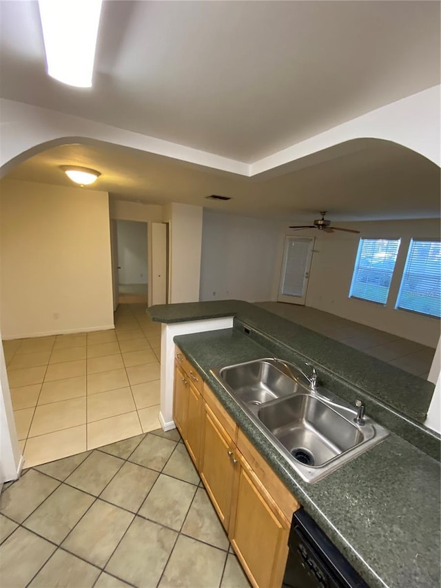 kitchen featuring arched walkways, ceiling fan, light tile patterned floors, a sink, and dark countertops