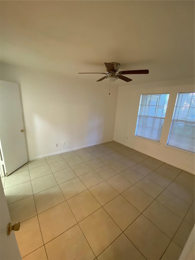 empty room with light tile patterned flooring and a ceiling fan