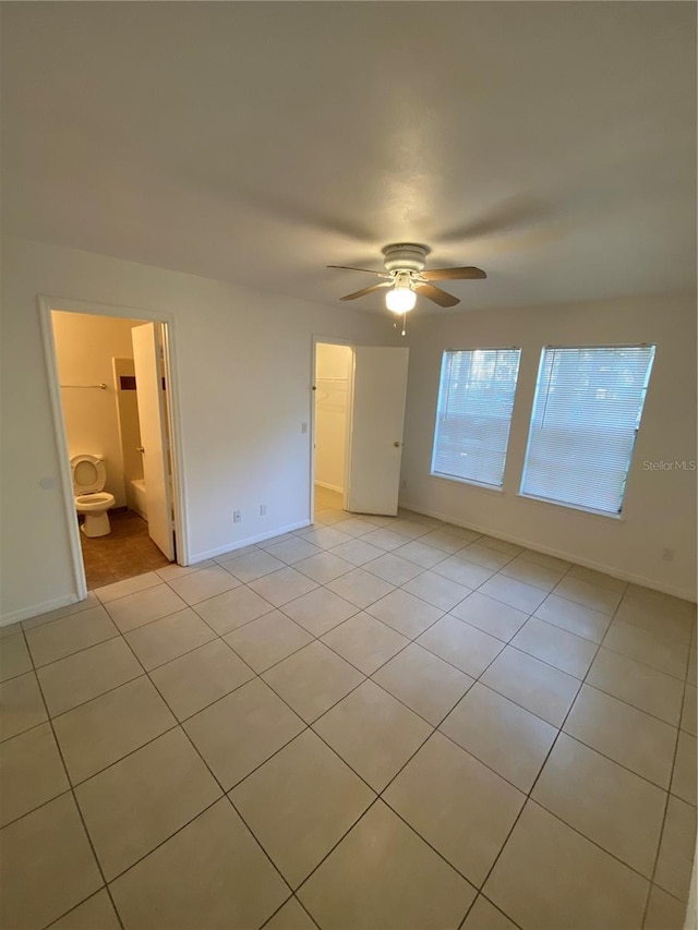 unfurnished bedroom featuring ceiling fan, a spacious closet, baseboards, and light tile patterned flooring