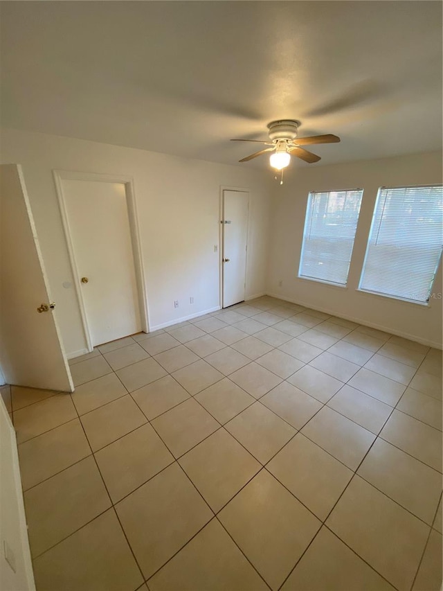 unfurnished room featuring light tile patterned floors, ceiling fan, and baseboards