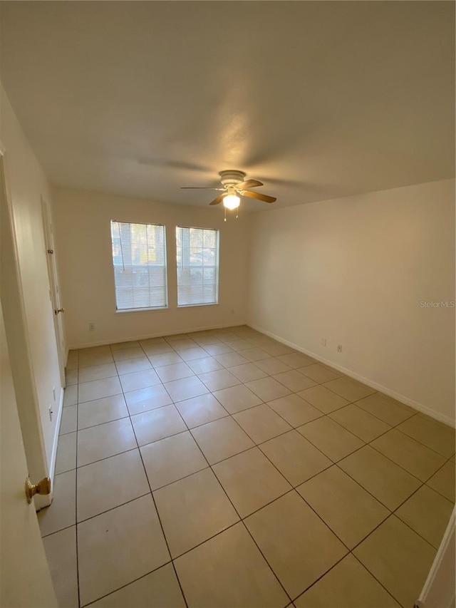 empty room featuring light tile patterned floors, baseboards, and a ceiling fan