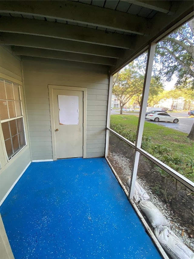 unfurnished sunroom featuring beam ceiling