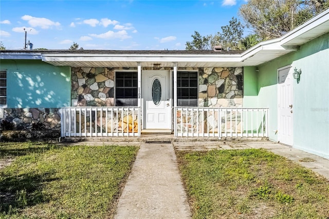 property entrance featuring stone siding and covered porch