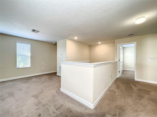 interior space with carpet, visible vents, baseboards, and an upstairs landing