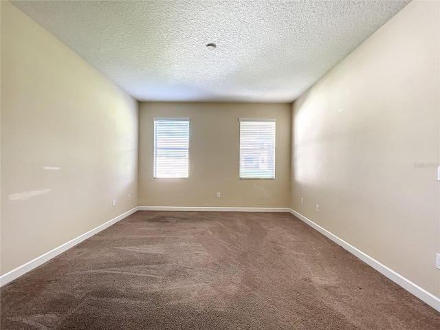 carpeted spare room featuring a textured ceiling and baseboards