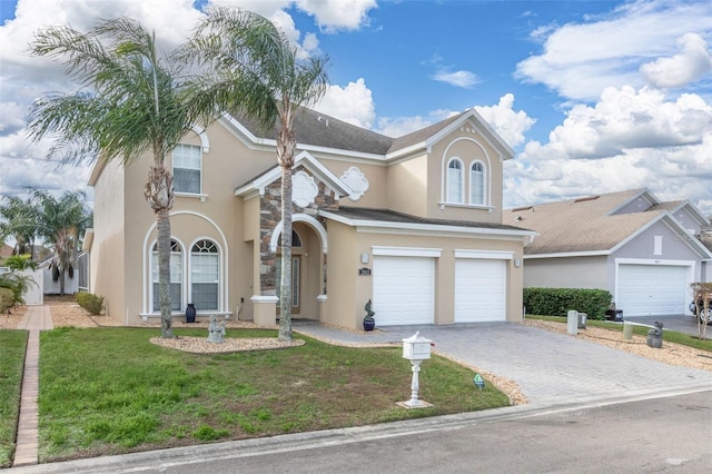 view of front facade featuring a front yard, stucco siding, decorative driveway, stone siding, and an attached garage