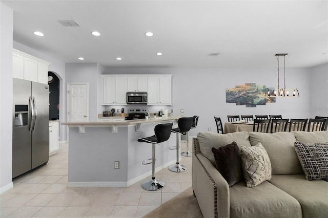 kitchen with a breakfast bar area, light countertops, light tile patterned floors, appliances with stainless steel finishes, and white cabinets