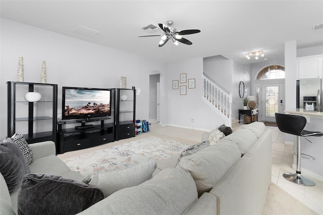 living area featuring visible vents, arched walkways, light tile patterned flooring, and stairs