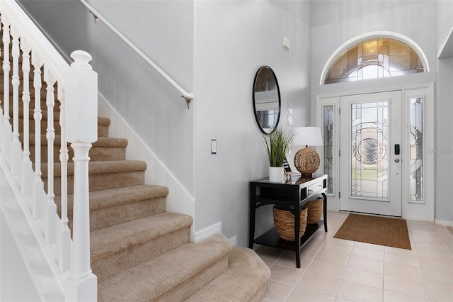 foyer entrance with light tile patterned floors, a high ceiling, and baseboards