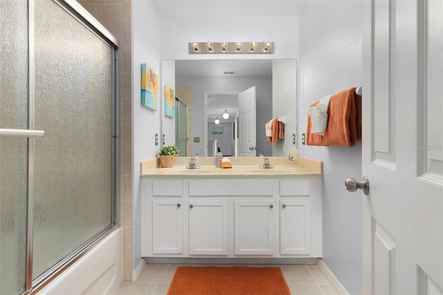 bathroom with tile patterned floors, combined bath / shower with glass door, double vanity, and a sink