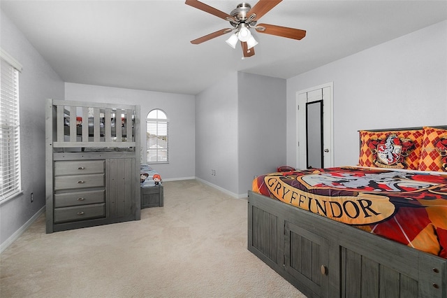 bedroom featuring light colored carpet, baseboards, and ceiling fan