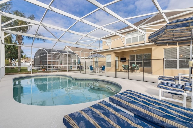 outdoor pool featuring glass enclosure, a patio, and ceiling fan