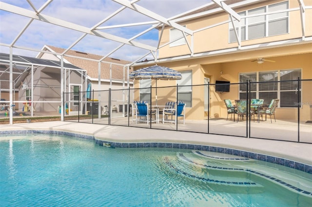 pool featuring glass enclosure, a ceiling fan, and a patio