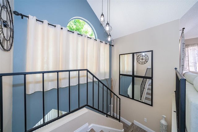 stairway featuring a healthy amount of sunlight, vaulted ceiling, and baseboards