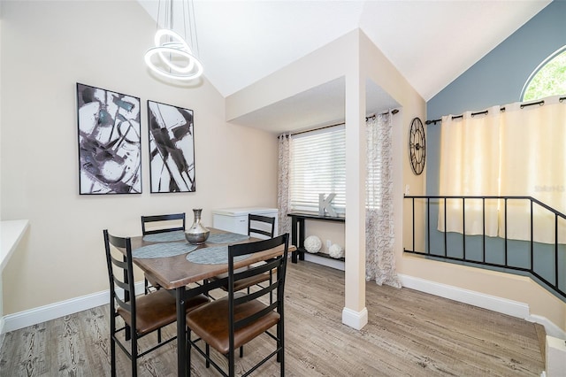 dining area with a notable chandelier, baseboards, vaulted ceiling, and wood finished floors