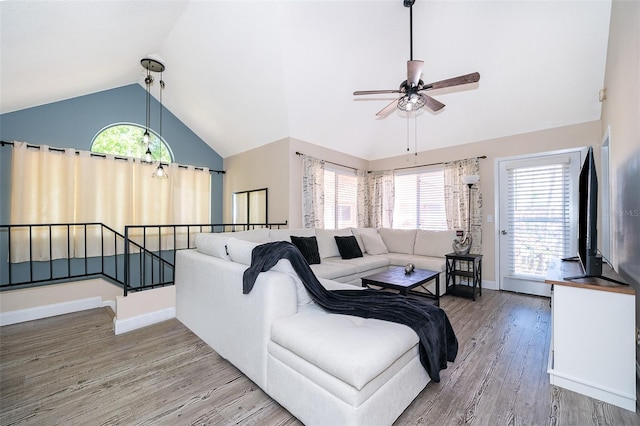 living area featuring baseboards, vaulted ceiling, a wealth of natural light, and wood finished floors