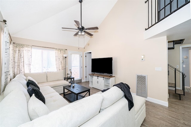 living room featuring high vaulted ceiling, visible vents, baseboards, and wood finished floors