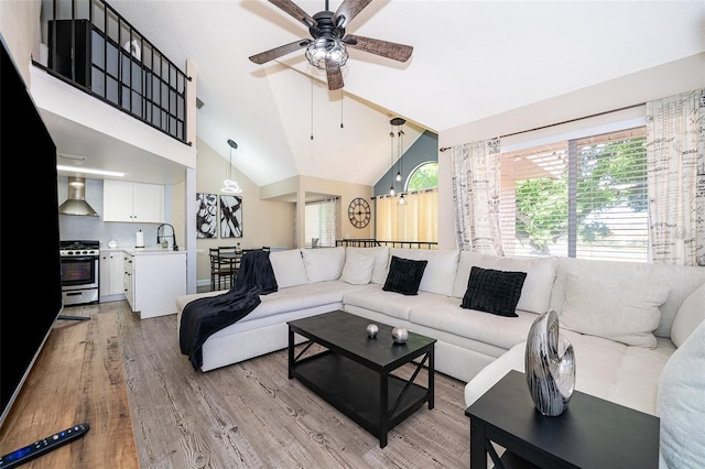 living room with lofted ceiling, ceiling fan, and light wood-style floors