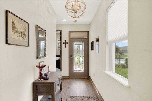 foyer entrance with baseboards, an inviting chandelier, and wood finished floors