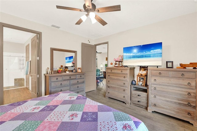 bedroom featuring visible vents, ensuite bath, wood finished floors, and a ceiling fan