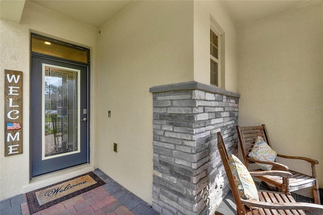 doorway to property featuring stone siding and stucco siding