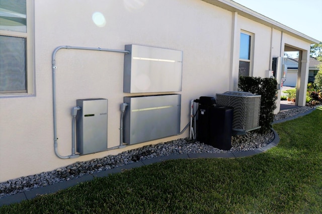 view of side of home with stucco siding, cooling unit, and a lawn