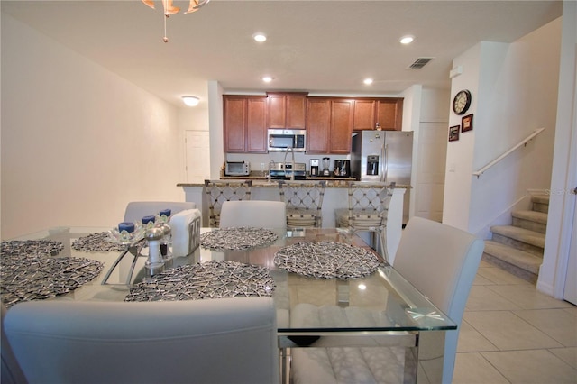 kitchen featuring light tile patterned floors, visible vents, brown cabinets, stainless steel appliances, and recessed lighting