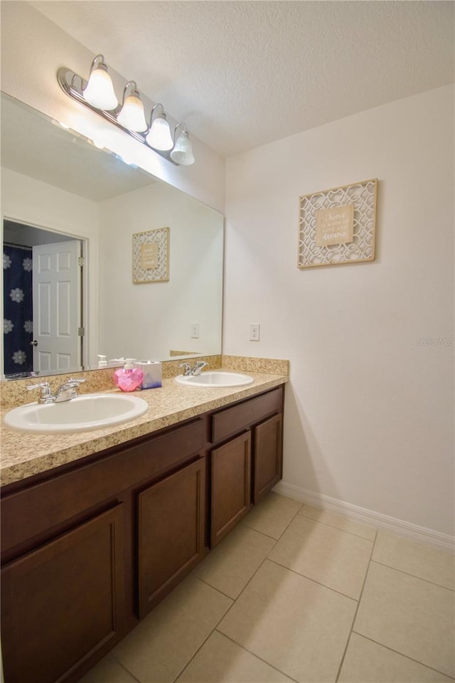 full bathroom with tile patterned floors, a sink, a textured ceiling, and double vanity