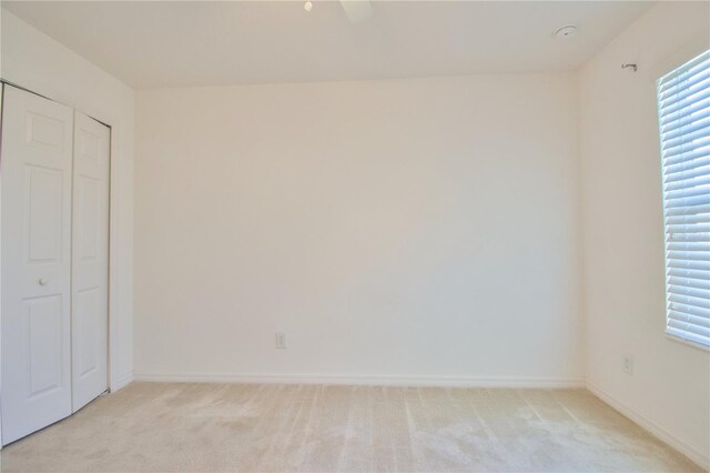 unfurnished bedroom with light carpet, a closet, and baseboards