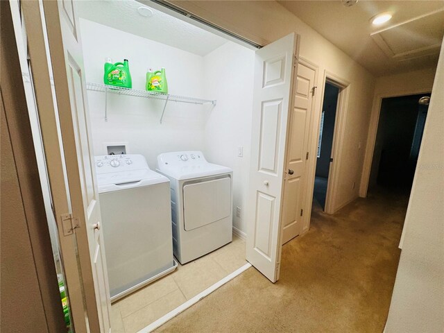 washroom with washing machine and clothes dryer, light tile patterned floors, attic access, light carpet, and laundry area