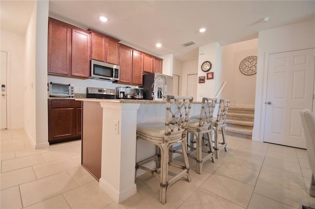 kitchen with stainless steel appliances, recessed lighting, a kitchen breakfast bar, and light tile patterned floors