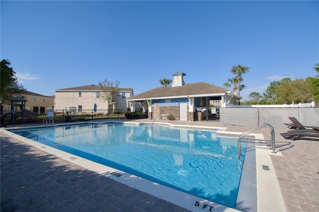 community pool with a patio area and fence