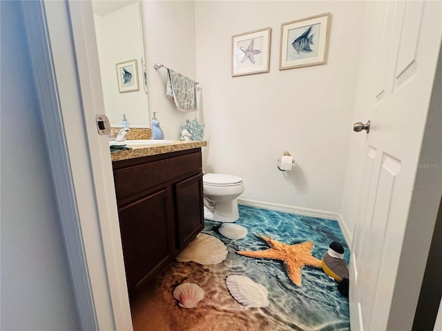 half bathroom featuring vanity, toilet, and baseboards