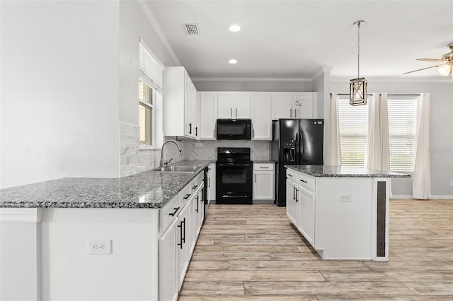 kitchen with black appliances, ornamental molding, dark stone countertops, and a sink