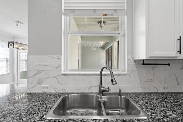 kitchen with tasteful backsplash, dark stone countertops, a sink, and white cabinetry