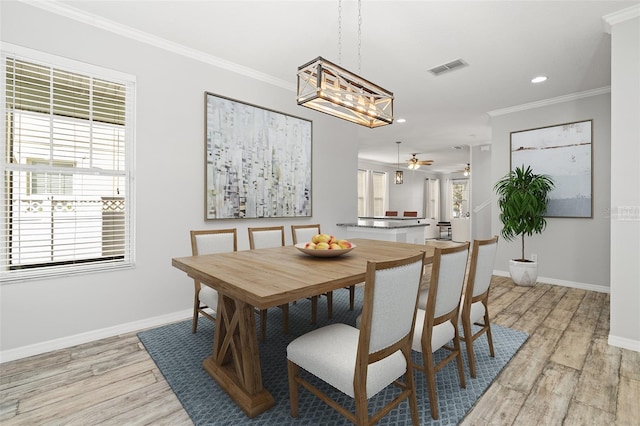 dining room with a wealth of natural light, ornamental molding, light wood finished floors, and visible vents