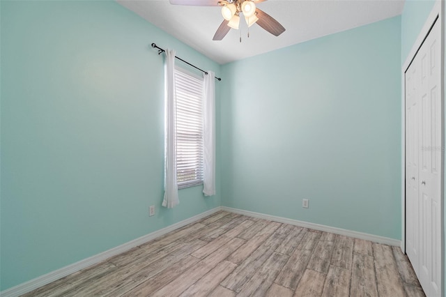 unfurnished bedroom featuring ceiling fan, a closet, light wood-type flooring, and baseboards