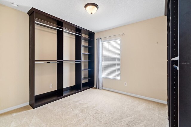 unfurnished bedroom with a textured ceiling, carpet flooring, and baseboards