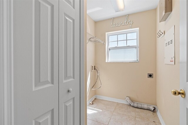 laundry area featuring laundry area, electric dryer hookup, baseboards, and light tile patterned floors