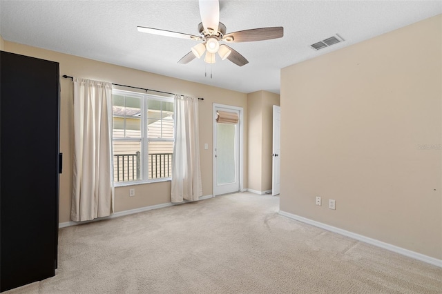 empty room featuring carpet floors, baseboards, visible vents, and a textured ceiling