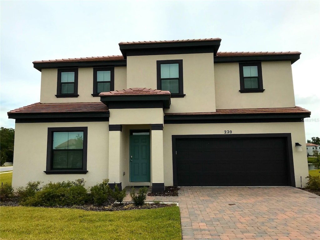 view of front of home with decorative driveway, an attached garage, and stucco siding