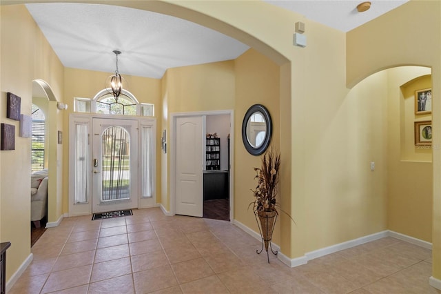 entrance foyer with an inviting chandelier, baseboards, and light tile patterned flooring