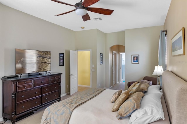 bedroom featuring arched walkways, ceiling fan, light colored carpet, visible vents, and baseboards