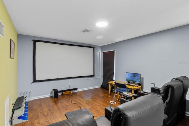 cinema room featuring visible vents, baseboards, and wood finished floors