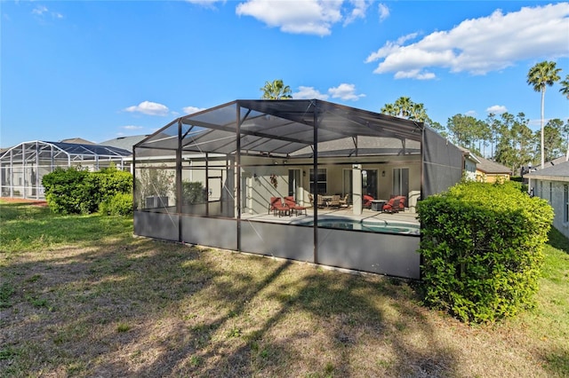 rear view of property with a lanai, a yard, an outdoor pool, and a patio