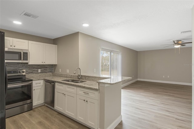 kitchen with stainless steel appliances, visible vents, a sink, and a peninsula