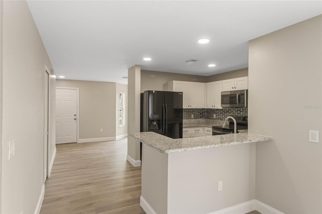 kitchen with light wood finished floors, tasteful backsplash, visible vents, white cabinets, and stainless steel appliances